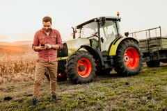 farmer working on field using smartphone in modern agriculture - tractor background royalty free stock image farmer working on field using smartphone in modern agriculture - tractor background royalty free stock image