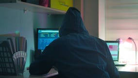 Male hacker internet working on a computer. man hacker in hood indoor hiding his Internet face stock footage Male hacker internet working on a computer. man hacker in hood indoor hiding his Internet face stock footage