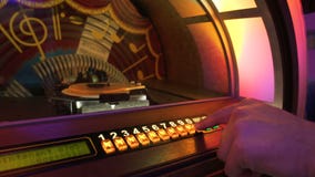 Male hand pushing buttons to play song on old musical box, selecting records