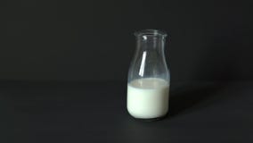 Male hand puts a glass of fresh milk on a black table
