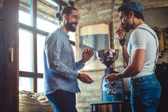 Male owners smiling while tasting coffee bean by the roaster royalty free stock photography Male owners smiling while tasting coffee bean by the roaster royalty free stock photography