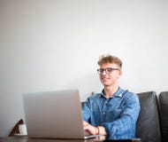 Young smiling man experience web content writer using laptop computer, sitting in office interior. stock photo Young smiling man experience web content writer using laptop computer, sitting in office interior. stock photo