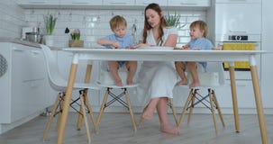 Maman avec deux enfants dans la cuisine ? la table pr?parant l'hamburger pour le d?jeuner banque de vidéos Maman avec deux enfants dans la cuisine ? la table pr?parant l'hamburger pour le d?jeuner banque de vidéos