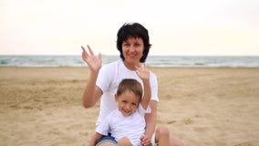 Maman heureuse et bébé s'asseyant sur une plage de mer ondulant et souriant, dans le mouvement lent banque de vidéos Maman heureuse et bébé s'asseyant sur une plage de mer ondulant et souriant, dans le mouvement lent banque de vidéos