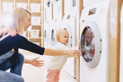 Mamman och behandla som ett barn i tvätteritagandesaker och spelar fotografering för bildbyråer Mamman och behandla som ett barn i tvätteritagandesaker och spelar fotografering för bildbyråer