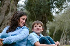 Mamá e hijo que se sientan en hierba verde en parque verde Concepto de relaciones de familia felices foto de archivo Mamá e hijo que se sientan en hierba verde en parque verde Concepto de relaciones de familia felices foto de archivo
