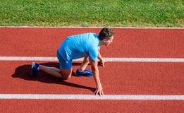 Man athlete stand low start position at stadium path. Beginning of new lifestyle habit. Runner ready to go. Athlete royalty free stock photography Man athlete stand low start position at stadium path. Beginning of new lifestyle habit. Runner ready to go. Athlete royalty free stock photography