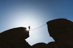 A man balancing walking on rope over precipice. Business, risk taking, challenge,bravery, and concentration stock photography A man balancing walking on rope over precipice. Business, risk taking, challenge,bravery, and concentration stock photography