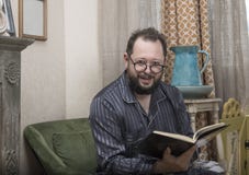 A man with a beard in his pajamas reads a book stock image A man with a beard in his pajamas reads a book stock image
