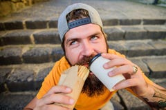 Man bearded eat tasty sausage. Urban lifestyle nutrition. Junk food. Carefree hipster eat junk food while sit stairs royalty free stock images Man bearded eat tasty sausage. Urban lifestyle nutrition. Junk food. Carefree hipster eat junk food while sit stairs royalty free stock images