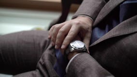 Man in brown suit looking at wrist watches