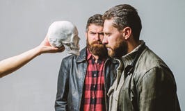Man brutal bearded hipster looking at skull symbol of death. Overcome your fears. Be brave. Focused on breaking fear stock photos Man brutal bearded hipster looking at skull symbol of death. Overcome your fears. Be brave. Focused on breaking fear stock photos