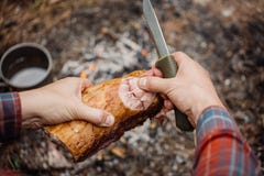 Man carving grilled rabbit meat in forest camp. Top view. royalty free stock image Man carving grilled rabbit meat in forest camp. Top view. royalty free stock image