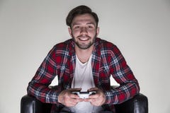 Man in a checkered shirt sitting in a leather armchair and holding a video game controller. royalty free stock photo Man in a checkered shirt sitting in a leather armchair and holding a video game controller. royalty free stock photo