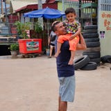 Man with a child in his arms near the tire shop, slums of Asia, residents of poor areas of the stock images Man with a child in his arms near the tire shop, slums of Asia, residents of poor areas of the stock images