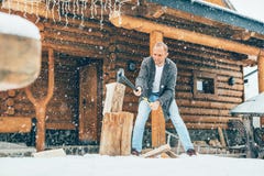 Man chopping wood on snowy yard for a house fireplace with heavy snowflakes background . Winter countryside holidays concept image stock photos Man chopping wood on snowy yard for a house fireplace with heavy snowflakes background . Winter countryside holidays concept image stock photos