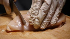The man cuts the chicken. The man cuts the chicken.