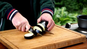Man cuts slices eggplant on cutting board. royalty free stock photo Man cuts slices eggplant on cutting board. royalty free stock photo