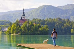 Man with a dog walks on the pier of Lake Bled, Slovenia