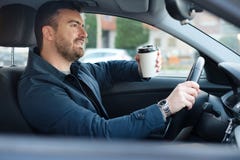 Man drinking coffee while driving the car Royalty Free Stock Photography Man drinking coffee while driving the car Royalty Free Stock Photography