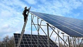 Male worker climbing the ladder to check solar panel.
