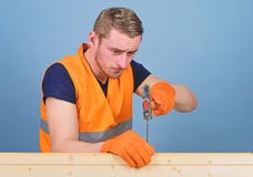 Man, faktotum i funktionsduglig likformig och skyddande handskar som handcrafting, ljus - blå bakgrund Snickare inredningssnickar royaltyfria bilder Man, faktotum i funktionsduglig likformig och skyddande handskar som handcrafting, ljus - blå bakgrund Snickare inredningssnickar royaltyfria bilder