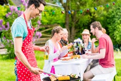 Man grilling meat on garden barbecue party