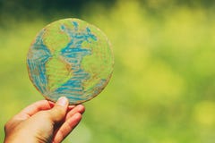 Man hand holding earth globe in front of outdoor green bokeh background. royalty free stock photo Man hand holding earth globe in front of outdoor green bokeh background. royalty free stock photo