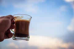 Man hand raising glass with morning coffee. Starting a good day concept. With cloudy sky in the background stock image Man hand raising glass with morning coffee. Starting a good day concept. With cloudy sky in the background stock image