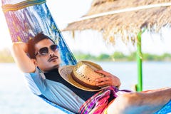 A man hold hat and sleep on hammock near the river. royalty free stock photography A man hold hat and sleep on hammock near the river. royalty free stock photography