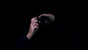 Man i den svarta maskeringen som gör foto vid kameran, hemlig information som begär lösenna royaltyfria bilder Man i den svarta maskeringen som gör foto vid kameran, hemlig information som begär lösenna royaltyfria bilder
