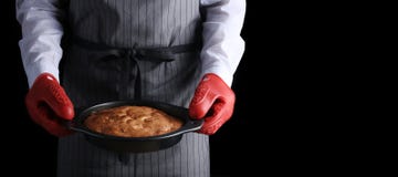 man i mörk bakgrund för röd potholderinnehavpaj och som isolerar på svart receptbegrepp med ingredienser på tabellen fotografering för bildbyråer man i mörk bakgrund för röd potholderinnehavpaj och som isolerar på svart receptbegrepp med ingredienser på tabellen fotografering för bildbyråer