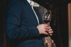 Man In A Blue Suit With A Skin Disease Holds Glass Of Red Wine. People Consider The Color Of The Wine And Try How It Royalty Free Stock Photos