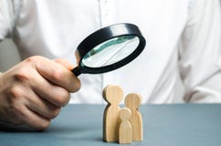 A man looks through a magnifying glass at a family figure. The study of family composition and demographic situation. Statistical stock images A man looks through a magnifying glass at a family figure. The study of family composition and demographic situation. Statistical stock images