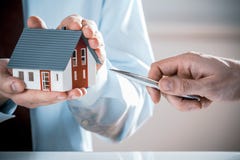 Man med Pen Pointing Miniature House av ett medel royaltyfri bild Man med Pen Pointing Miniature House av ett medel royaltyfri bild