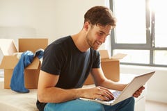 Man Moving Into New Home Using Laptop Computer royalty free stock photo Man Moving Into New Home Using Laptop Computer royalty free stock photo