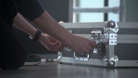 Man opens up aluminum dj travel set case. Portable audio mixing studio equipment in the metallic box. Man opens up aluminum dj travel set case. Portable audio mixing studio equipment in the metallic box.