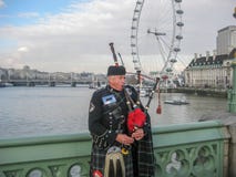 Man playing bagpipe, dressed in traditional scottish costume on banks of the River Thames stock photography Man playing bagpipe, dressed in traditional scottish costume on banks of the River Thames stock photography