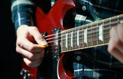 Man playing on electric guitar against dark background stock image Man playing on electric guitar against dark background stock image