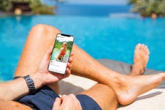 Man by the pool looking at social media app on his mobile phone Stock Images Man by the pool looking at social media app on his mobile phone Stock Images