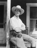 Man on porch wearing cowboy hat