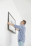 Man positioning picture frame on wall stock image Man positioning picture frame on wall stock image