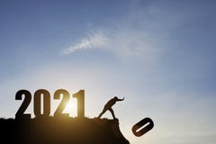 Man push number zero down the cliff where has the number 2021 with blue sky and sunrise. It is symbol of starting and welcome