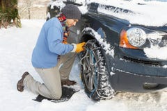 Man Putting Snow Chains Onto Tire of a car