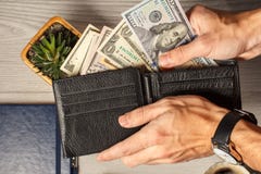 Man& x27;s hands holding black leather wallet full of dollar bills Stock Photo Man& x27;s hands holding black leather wallet full of dollar bills Stock Photo
