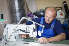 Man seamsrtess sitting at the sewing machine stock image Man seamsrtess sitting at the sewing machine stock image