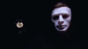 Man showing bitcoin, spooky anonymous mask on face, cyber attack, robbery stock video Man showing bitcoin, spooky anonymous mask on face, cyber attack, robbery stock video