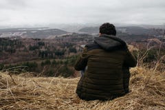 Man sitting on a hill looking at the horizon. stock image Man sitting on a hill looking at the horizon. stock image