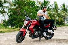Man sitting on his motorbike on palm background