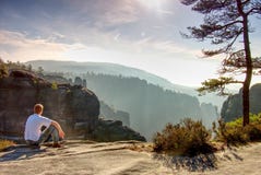 Man sitting on rock in mountain and watching sunrise stock photo Man sitting on rock in mountain and watching sunrise stock photo